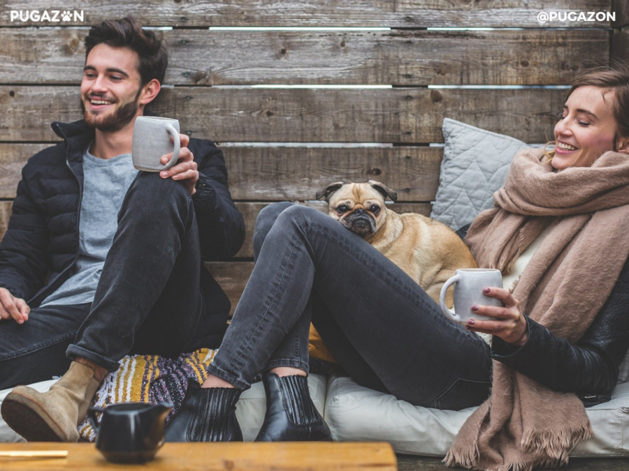 male and female pug dog breeders sitting down outside with a pug mix breeed dog